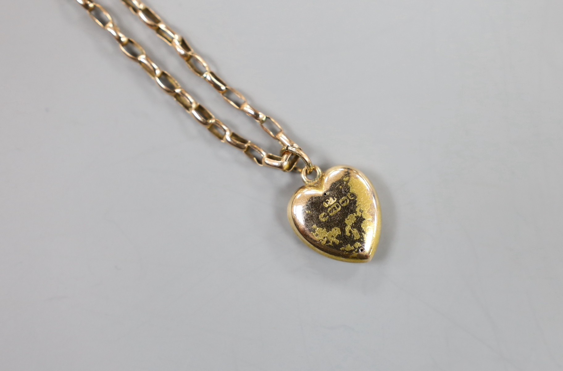 A yellow metal curb link necklace, 51cm, with a 15ct gold heart shaped charm, gross 5.6 grams